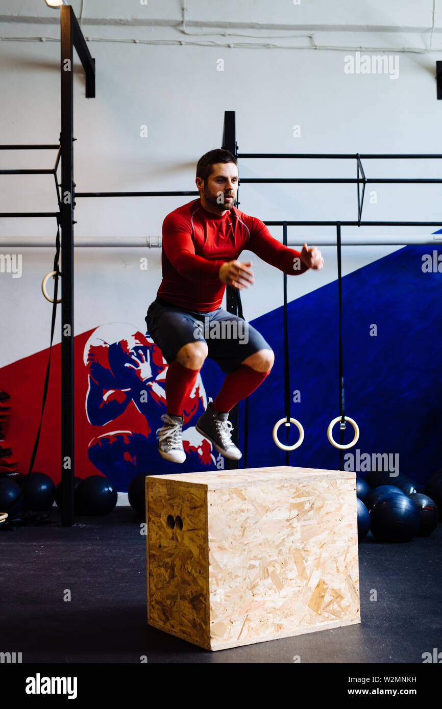 Athletic hombre saltando sobre cuadro saltar durante ejercicios de gimnasia Foto de stock