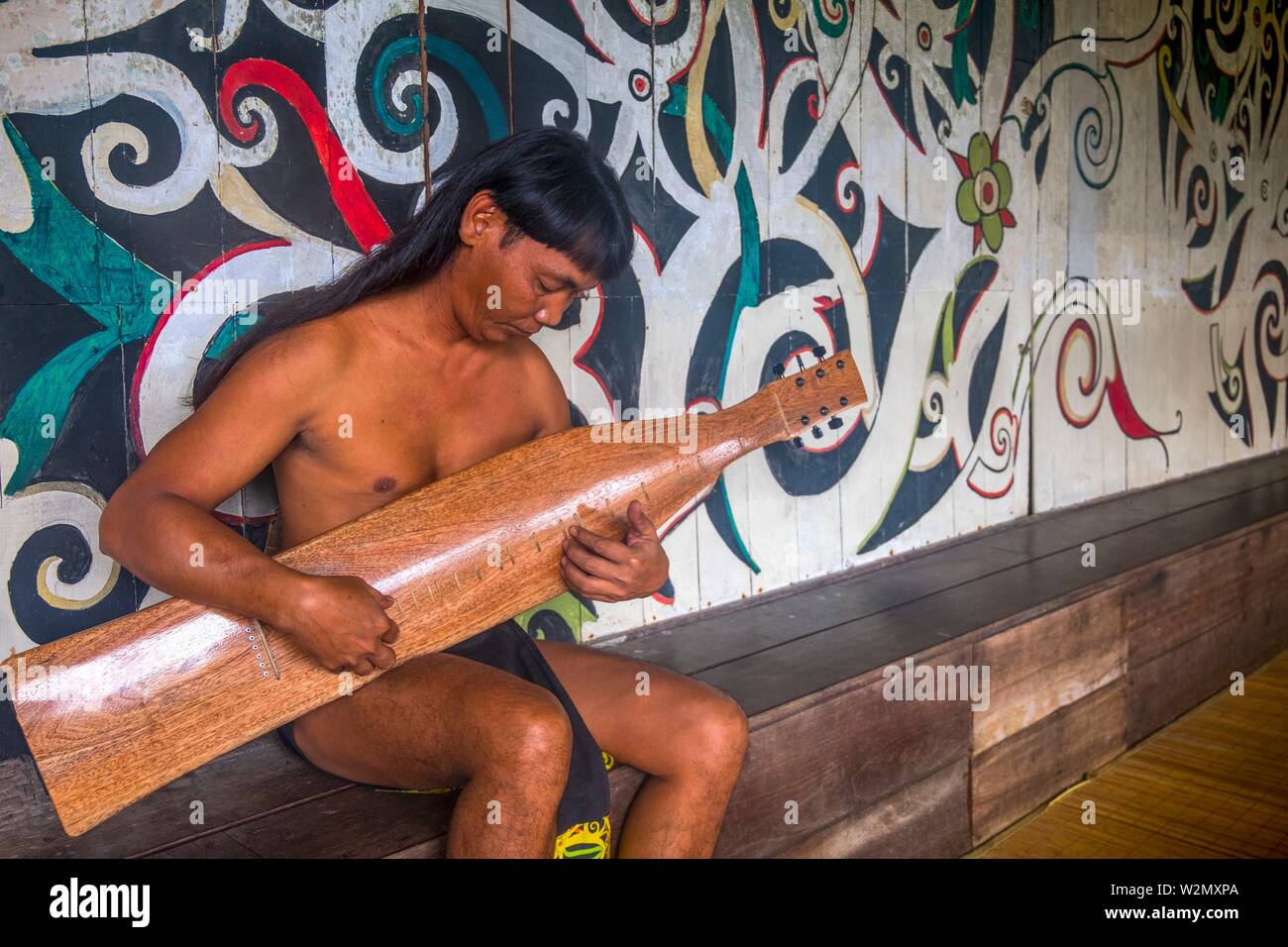 Malasia Kuching, Sarawak, en la Aldea Cultural, jugando 'ape'' Kanjet Borneo (guitarra). Foto de stock