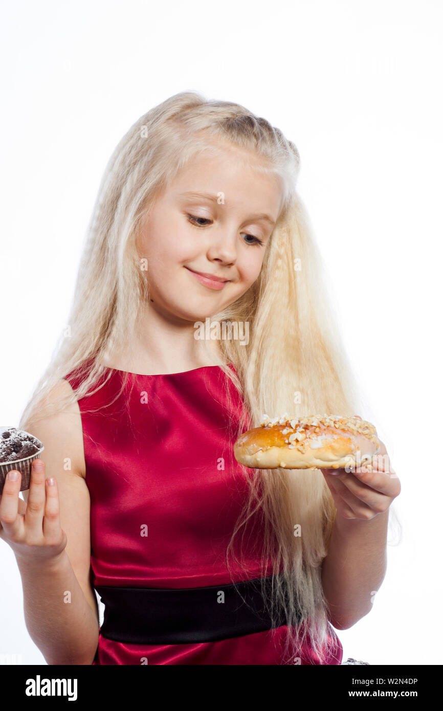 Chica hacer una elección entre dos tortas. Aislado sobre fondo blanco. Foto de stock