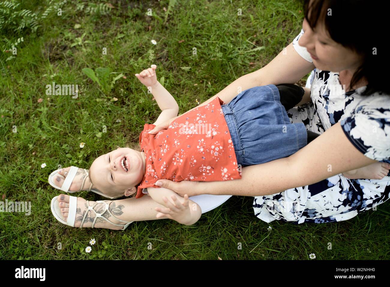 La abuela de mediana edad jugando con su nieta bebé niño afuera, en Meadow en estacionamiento Foto de stock