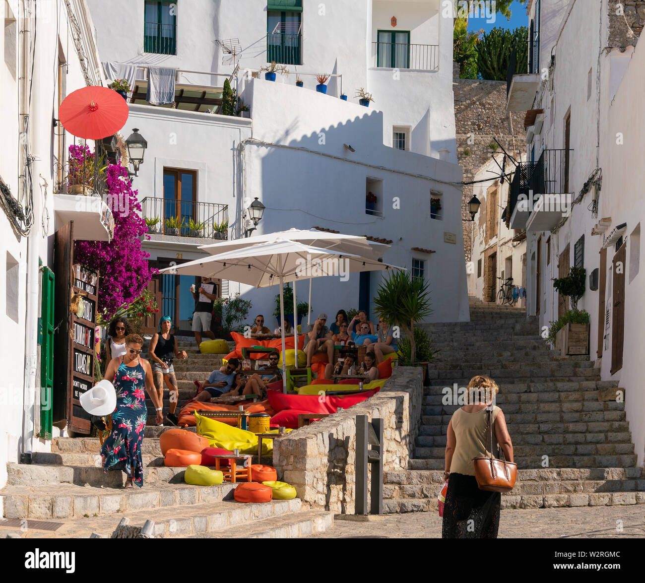 22 de junio del 2019 - Ibiza, España. La gente relajándose en el colorido  suave bolsas de frijol bajo sombrillas en la S'Escalinata Bar ubicado en la  ciudad de Ibiza Fotografía de
