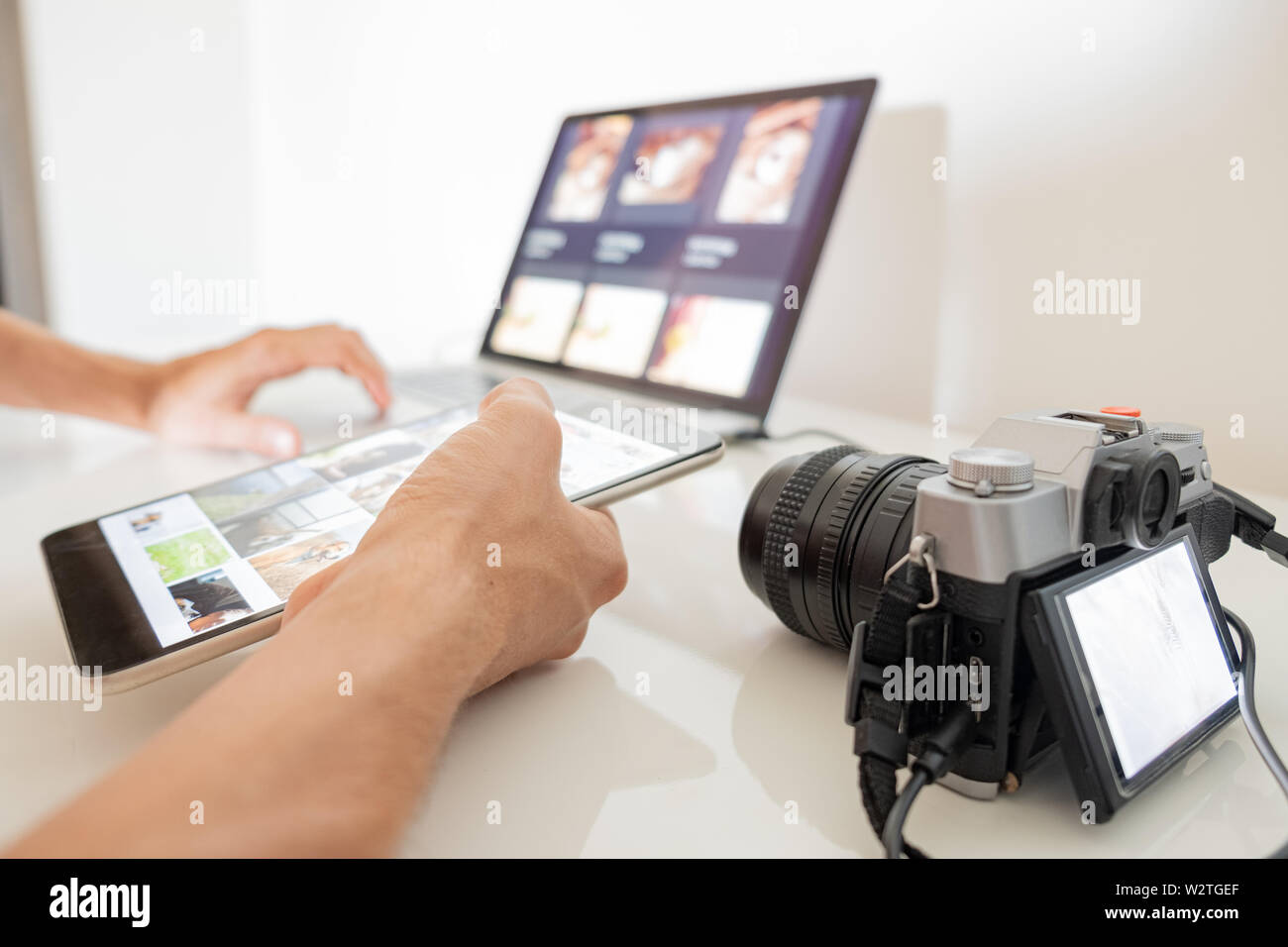 Administración de imágenes digitales en un ordenador. Derechos manos sostienen una tableta para organizar o importar imágenes desde la cámara al ordenador portátil Foto de stock