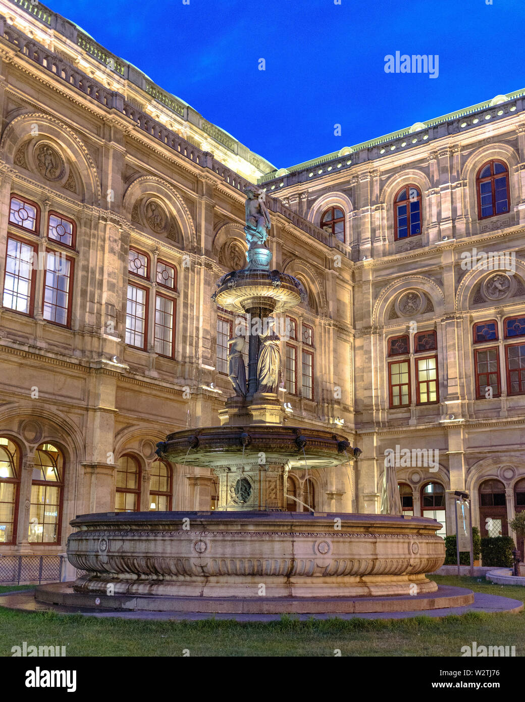 La fuente Opernbrunzer antes de la Ópera Estatal de Viena en la hora azul en el verano Foto de stock