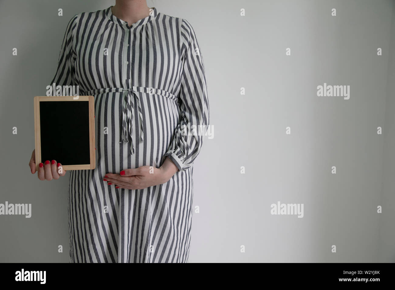 Una mujer embarazada sosteniendo un blak pizarra cerca de ella embarazada vientre Foto de stock