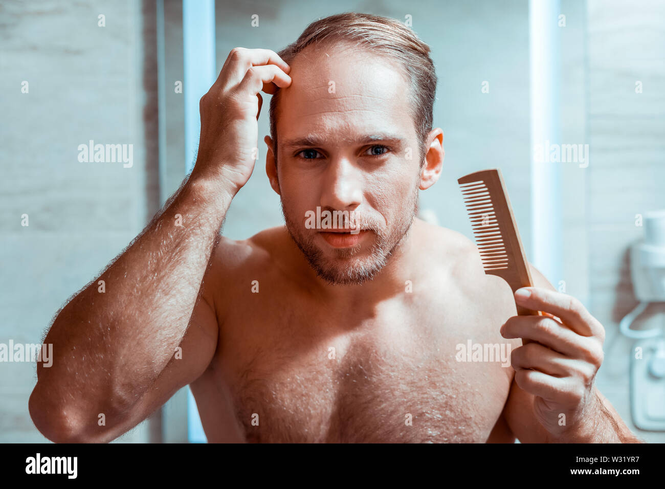 Diligente de pelo corto hombre corrigiendo su peinado con cepillo pequeño  Fotografía de stock - Alamy