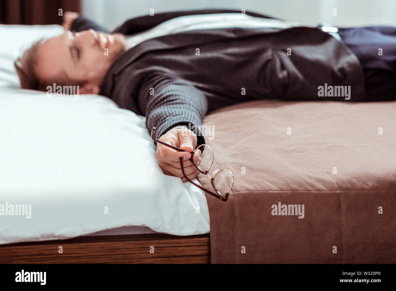 Cansado de pelo corto hombre tumbado en la cama en un disfraz Fotografía de  stock - Alamy
