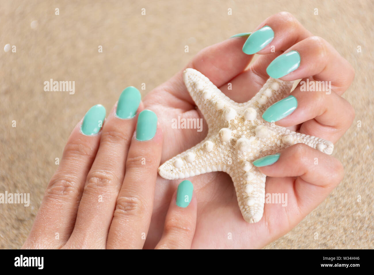 Chica manos con un color turquesa uñas holding polaco starfish y arena de  mar en el fondo. Concepto de belleza y manicura. Cerca, el enfoque  selectivo Fotografía de stock - Alamy