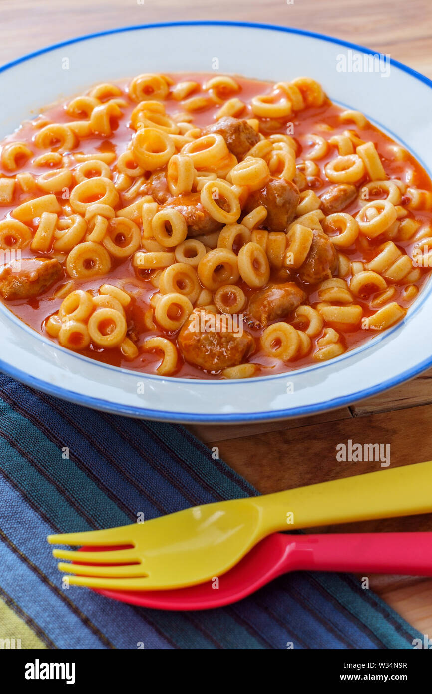Comidas infantiles enlatados anillos espagueti con albóndigas y coloridos  utensilios Fotografía de stock - Alamy