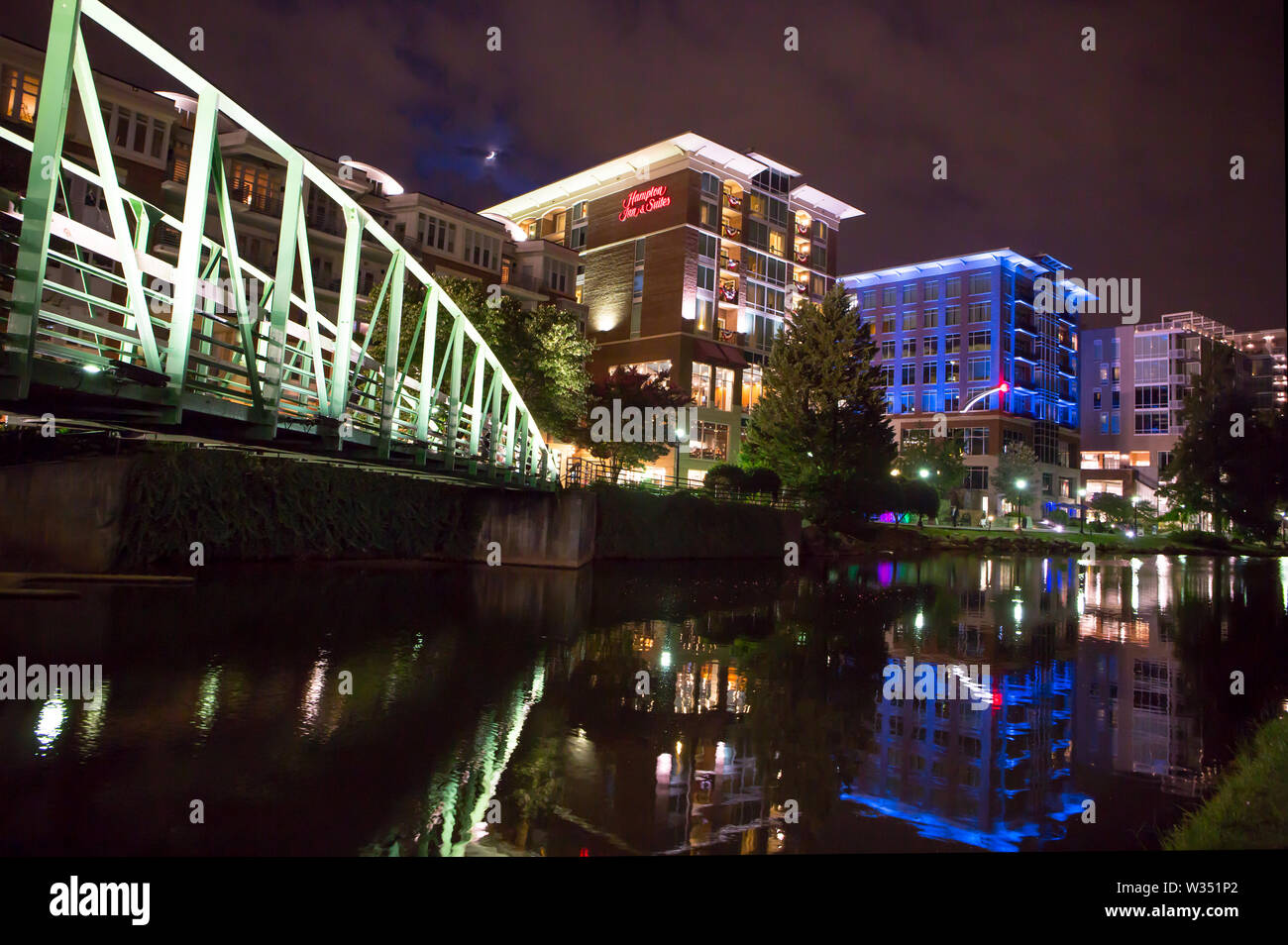 GREENVILLE, SC (USA) - Julio 5, 2019: Una vista nocturna del centro de River Walk con el río Coloque el desarrollo de hoteles, restaurantes y tiendas. Foto de stock