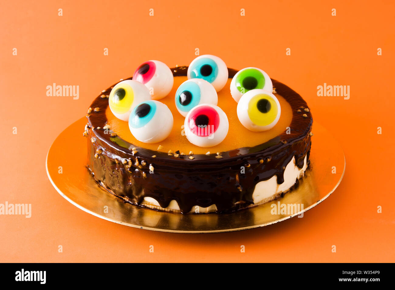 Pastel de Halloween con dulces ojos decoración sobre fondo naranja  Fotografía de stock - Alamy