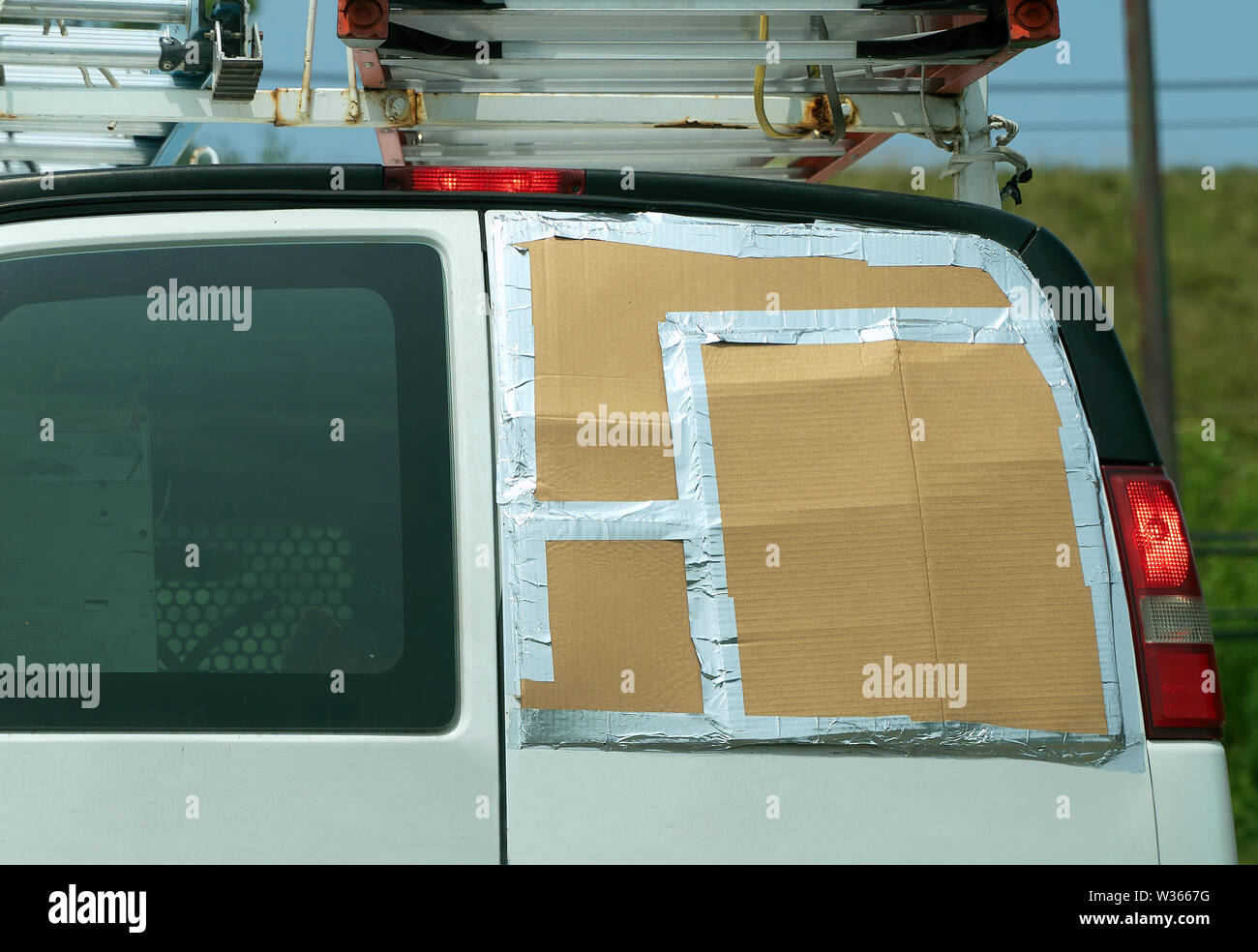 Un temporal de cartón y cinta adhesiva de aluminio de solución en esta furgoneta con la falta de una ventana trasera. Foto de stock