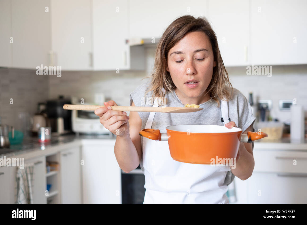 Mujer joven degustación de alimentos en el hogar cocina Foto de stock