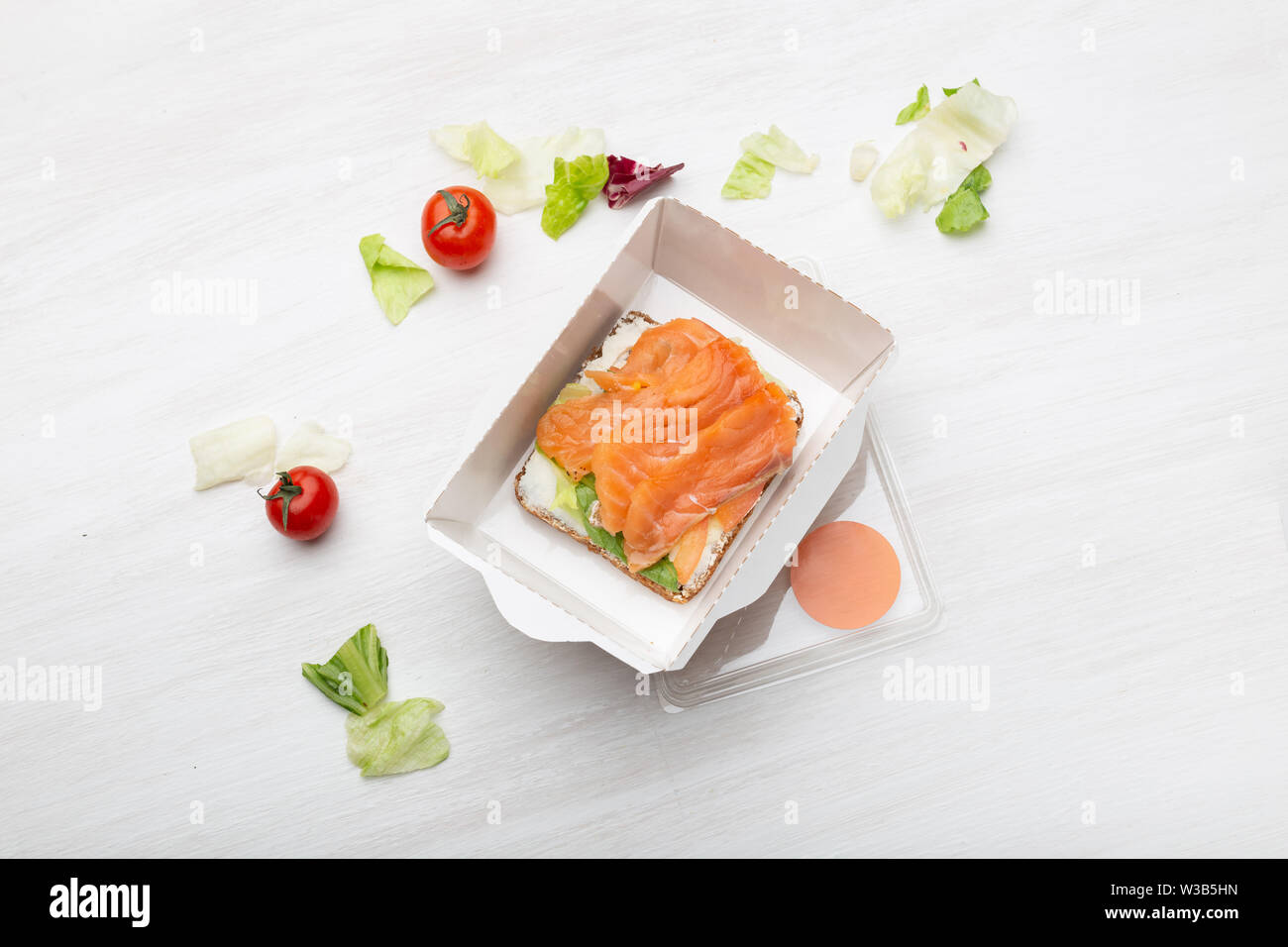 https://c8.alamy.com/compes/w3b5hn/vista-superior-de-sandwich-con-queso-blando-y-el-pez-rojo-se-encuentra-en-la-caja-de-almuerzo-junto-a-los-verdes-y-los-tomates-en-una-tabla-en-blanco-concepto-de-un-refrigerio-saludable-w3b5hn.jpg