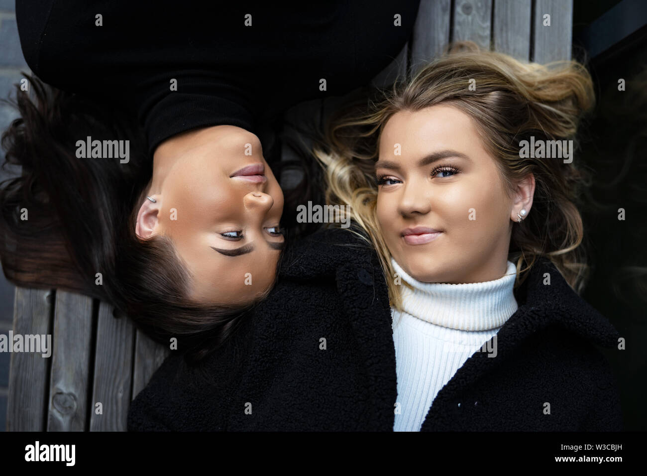 Close-up retrato de dos mejores amigos sonriente tumbado sobre un banco de trabajo Foto de stock