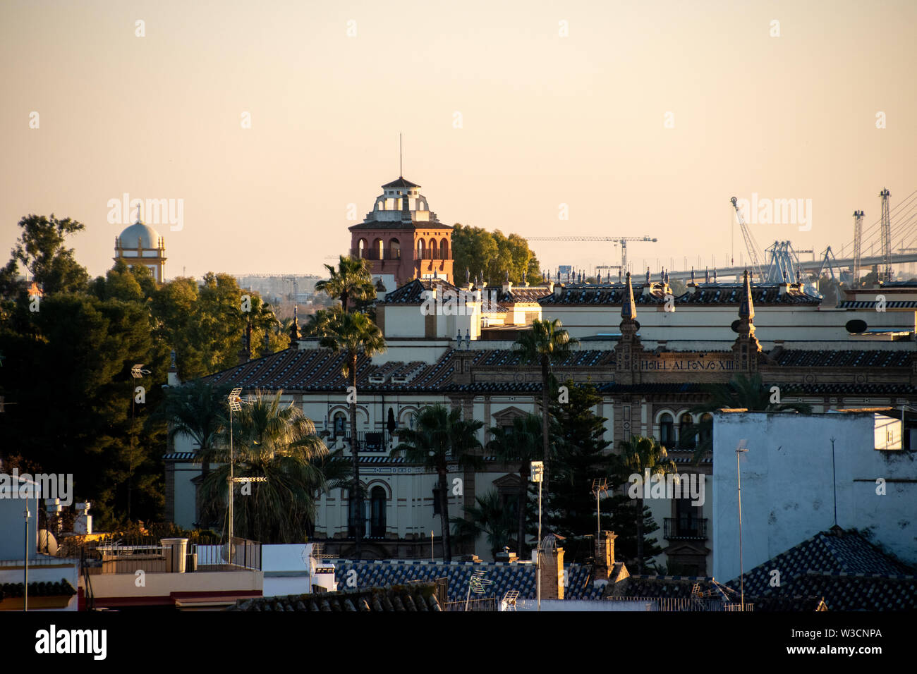 Una vista de la ciudad española de Sevilla durante una puesta de sol naranja con el Hotel Alfonso llegando a través de los edificios Foto de stock