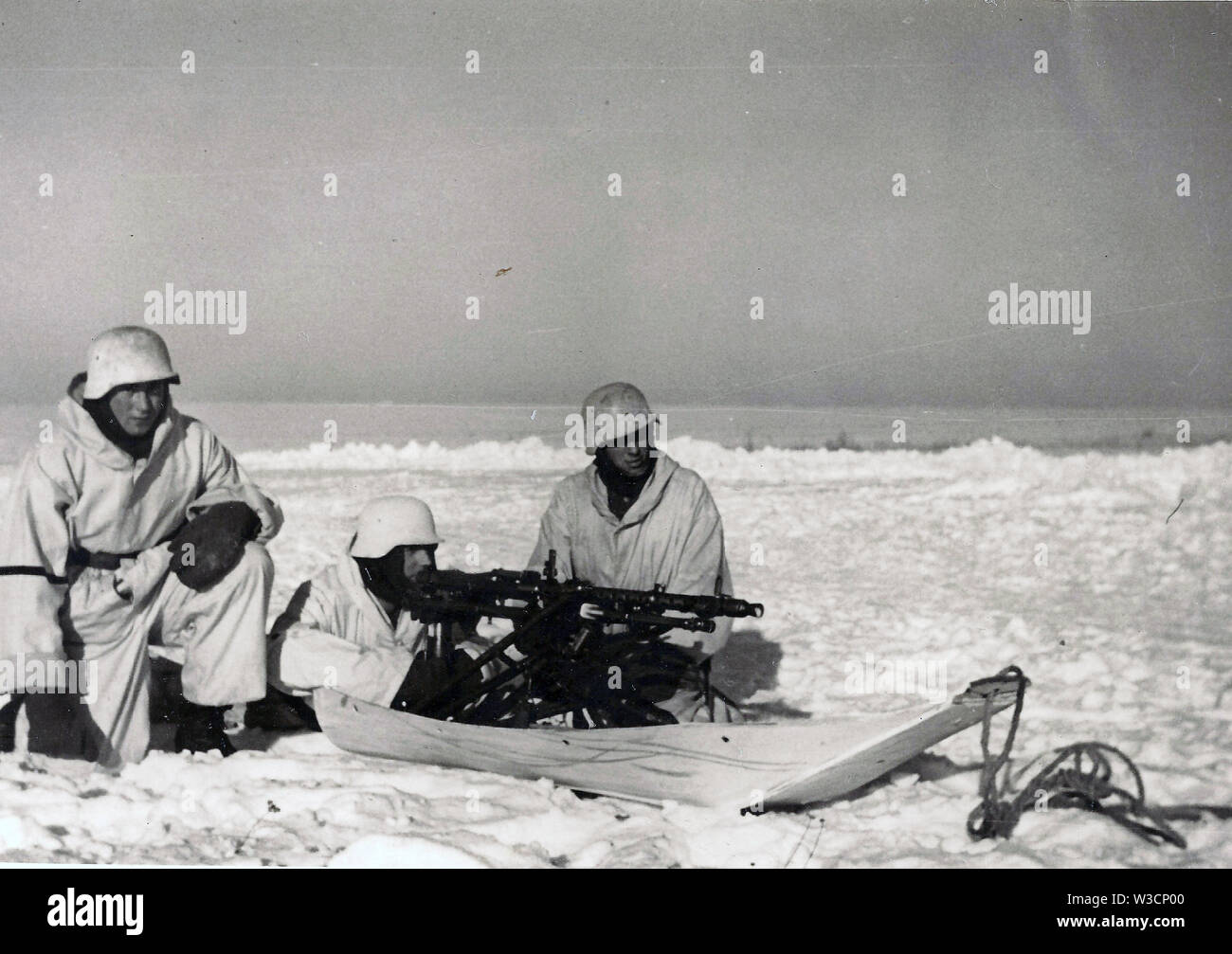 Los soldados alemanes en camuflaje invernal blanco con una ametralladora pesada MG34 montada en un trineo en una gruesa capa de nieve en el frente ruso de 1942 Foto de stock