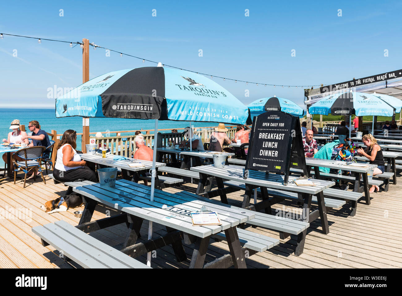 Los turistas relajarse y disfrutar del sol en la terraza de Fistral Beach Bar en Newquay en Cornualles. Foto de stock
