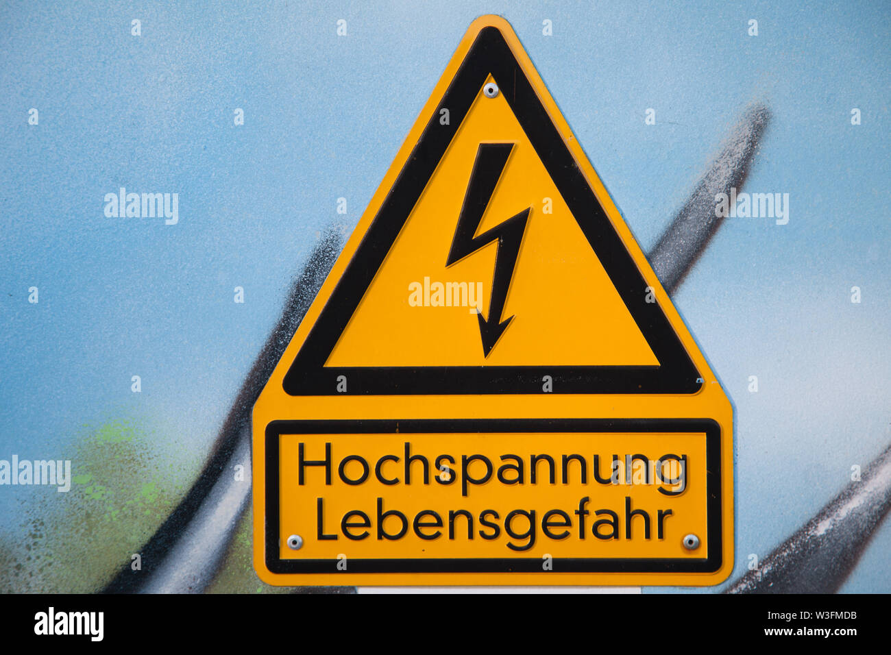 Close-up de una señal de advertencia de voltaje alto alemán montado en una pared. Foto de stock