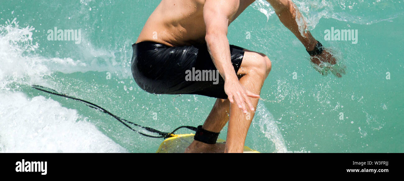 Un surfista cabalgando una ola y tener su mano dentro de la onda en los trópicos Foto de stock