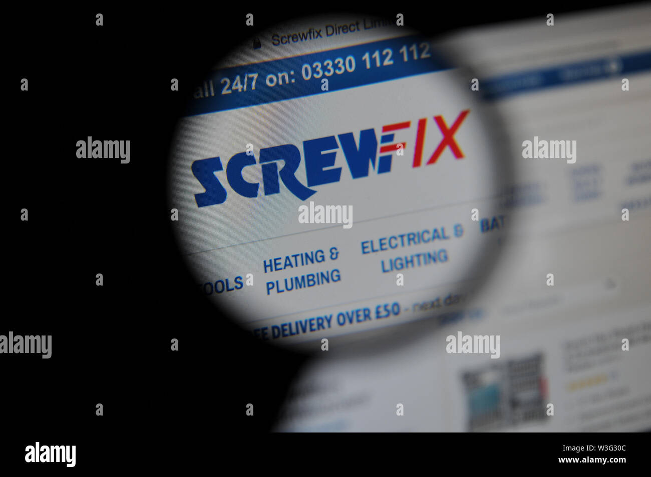 El sitio web de Screwfix vistos a través de una lupa Foto de stock