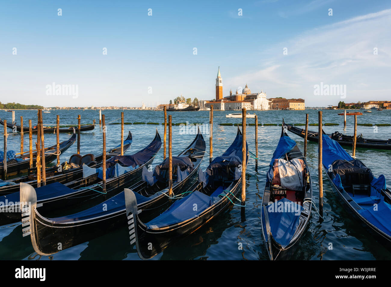 Fila de góndolas amarradas junto a la Riva degli Schiavoni contra barcos y la isla de San Giorgio Maggiore, Venecia, Italia Foto de stock
