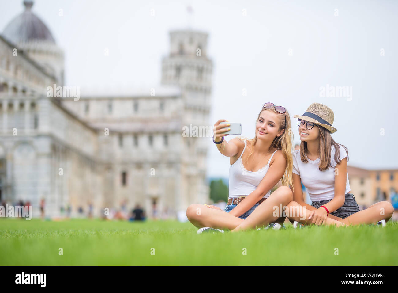 Las niñas adolescentes jóvenes turista viajero antes de Pisa Torre selfie para smartphone imagen o vídeo. Foto de stock