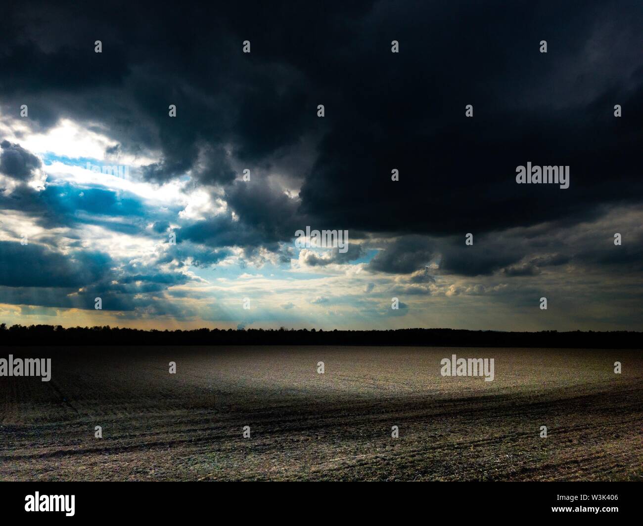Oscuro cielo nublado con sol brille sobre campo en atmósfera oscura Foto de stock