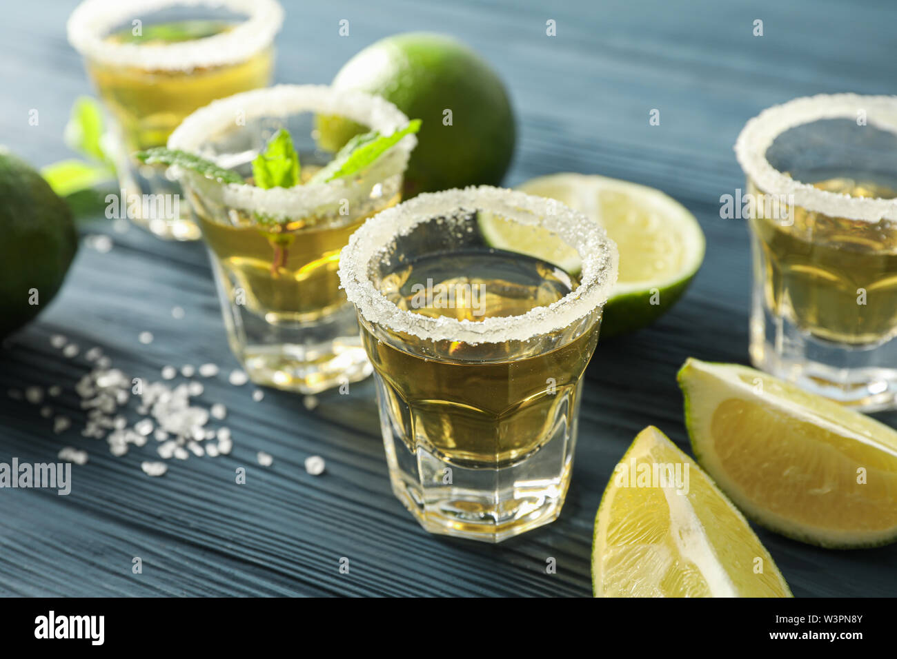 Tragos de tequila con rodajas de limón y menta sobre fondo de madera azul de stock -