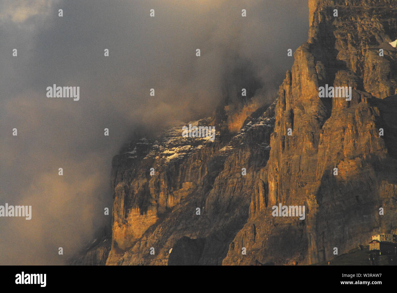 Vida de montaña en los Alpes Suizos. Nota Los edificios de un pueblo en la parte inferior derecha. Una imponente montaña en increíble luz del atardecer. Foto de stock