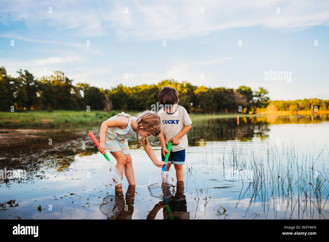Niña ayudando a boy atrapar un pez en su red en el lago Foto de stock