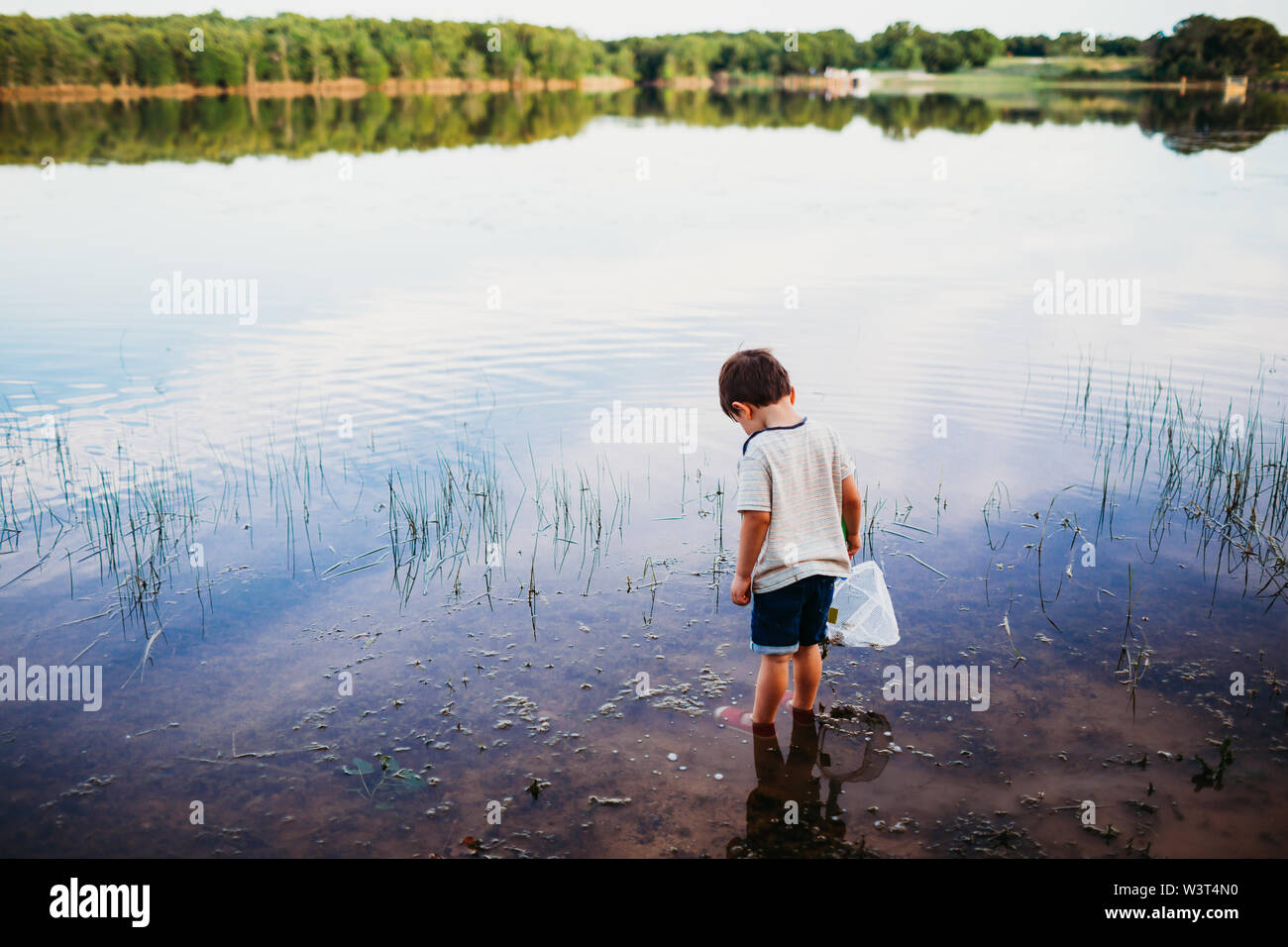 Joven de pie en el lago solo buscando pescado Foto de stock