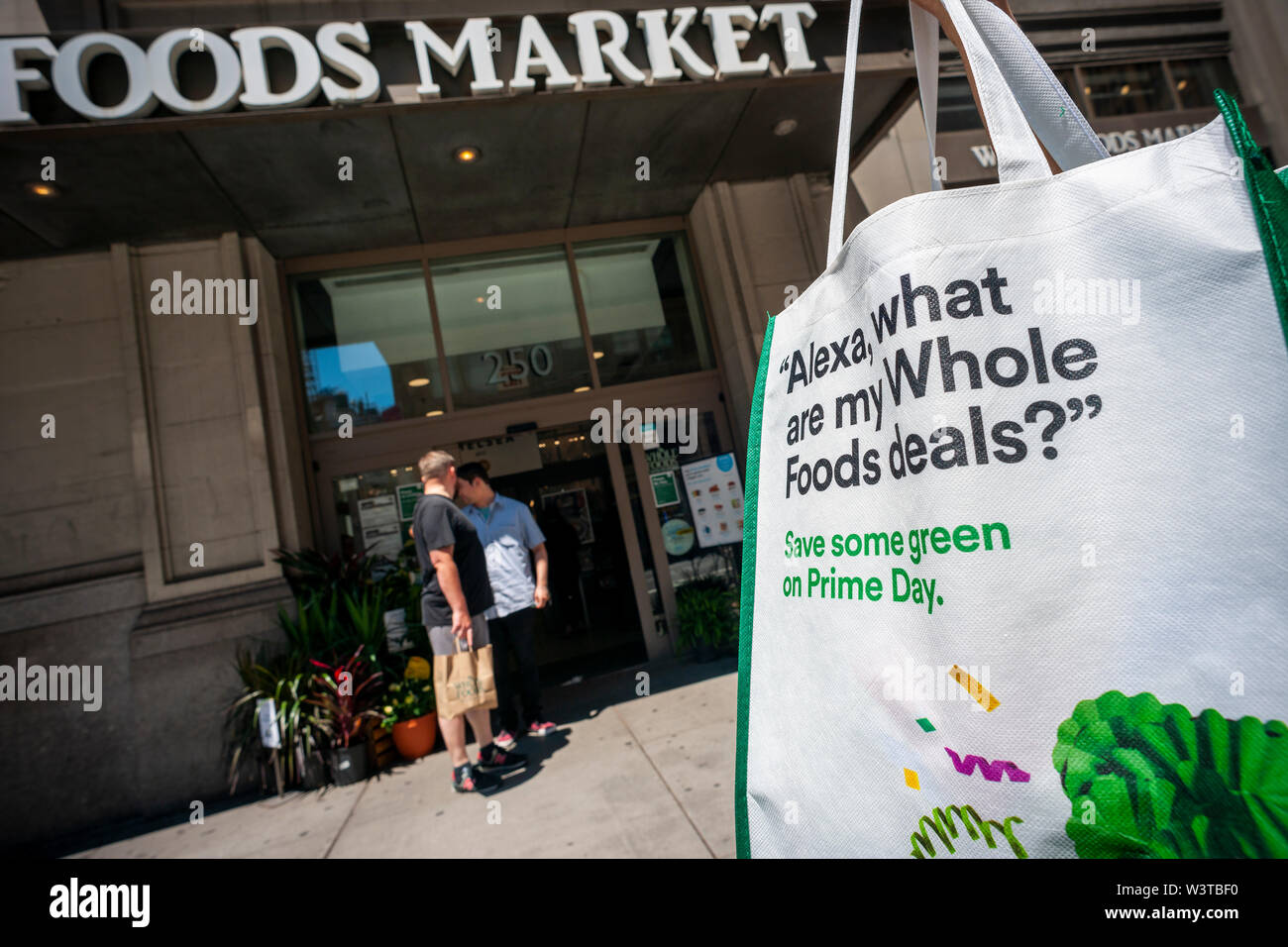 Un miembro de la prima del Amazonas con su bolsa de compras de souvenirs  pasa Whole Foods Market en Chelsea en Nueva York en el Amazonas de la  autoproclamada "Primer día de