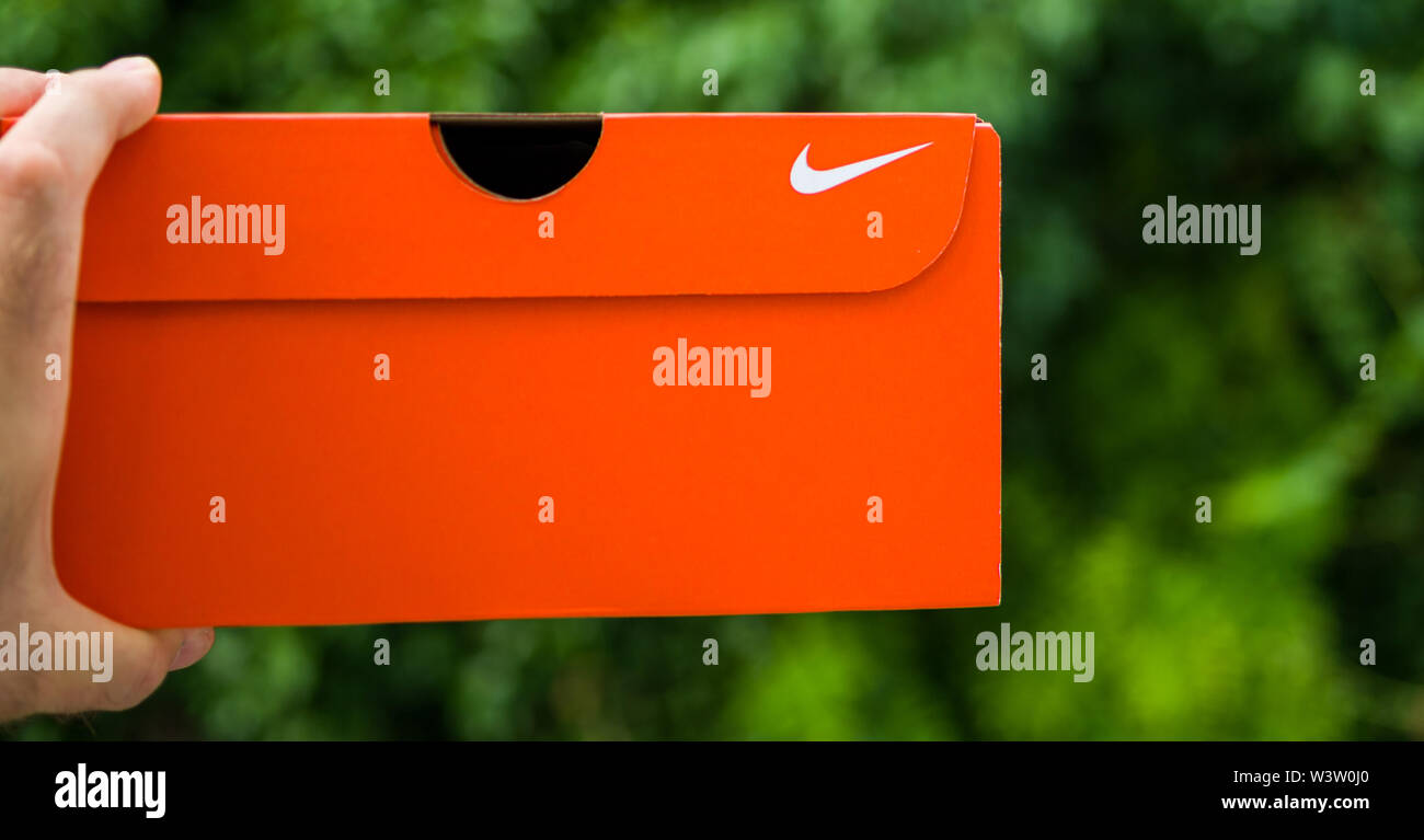 París, Francia - Jul 13 2019: el hombre mano sujetando las nuevas  zapatillas Nike caja de cartón equipos fabricados por NIKE SPORTSWEAR vista  lateral de la caja logotipo de la marca Fotografía