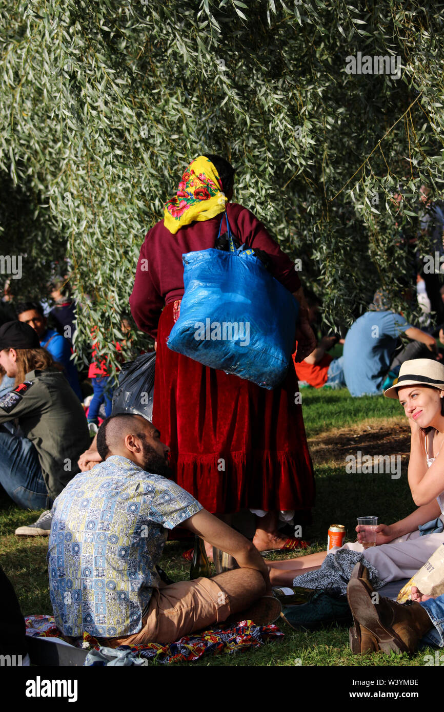 Vista trasera de una mujer romaní de Rumania recolectando botellas y latas de depósito en Tokoinranta en Kallio Block Party 2016 en Helsinki, Finlandia Foto de stock