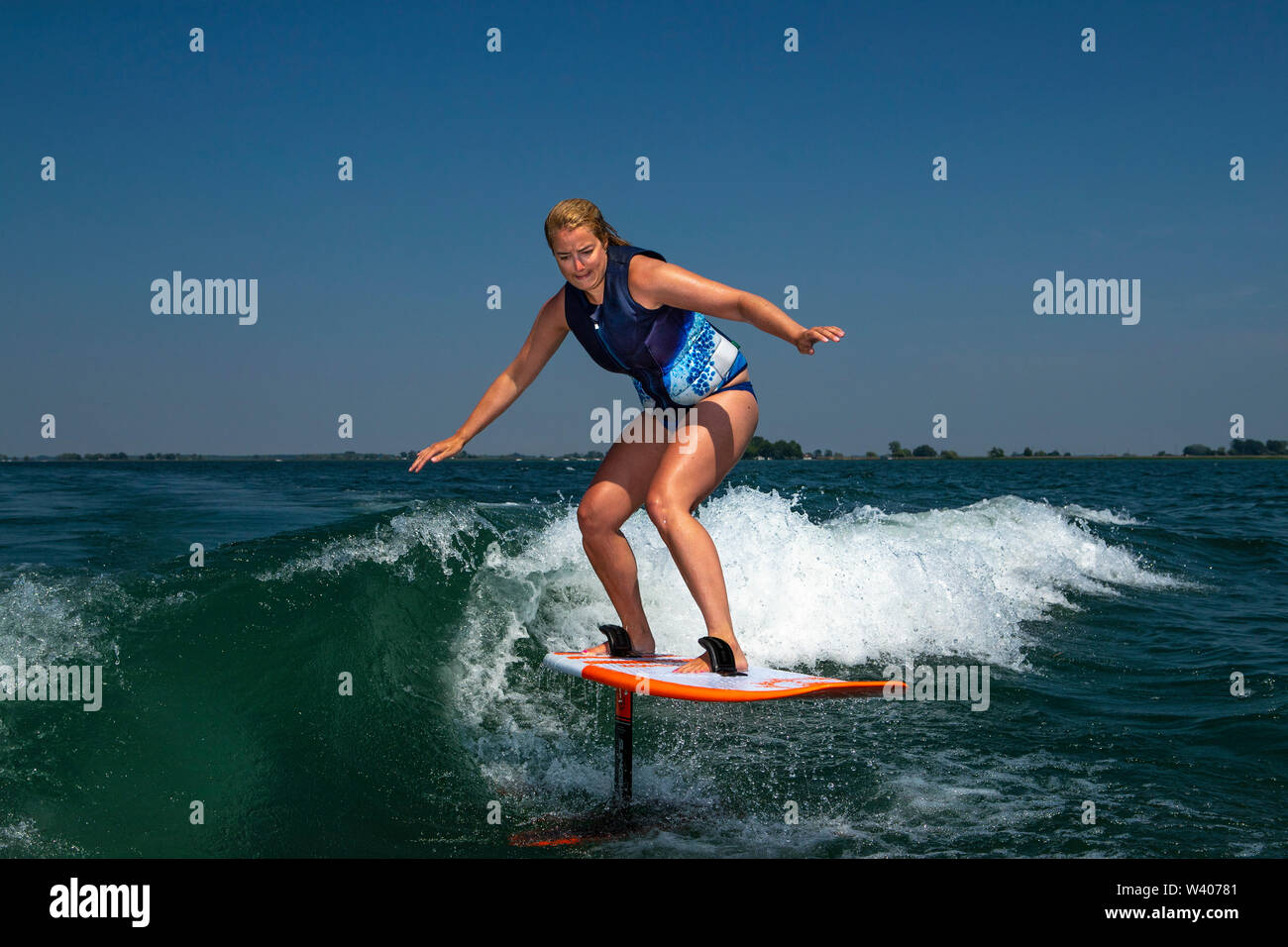 Una mujer que monta a una lámina de la junta mientras wake surf. Foto de stock