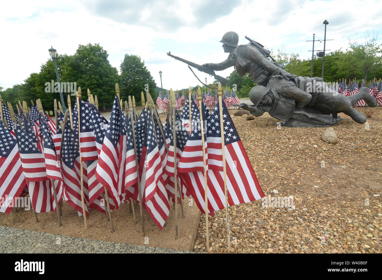 Con pequeñas banderas americanas muestra en primer plano, una estatua de un soldado ayudando a un compañero herido en el Día-D Memorial en Virginia. Foto de stock