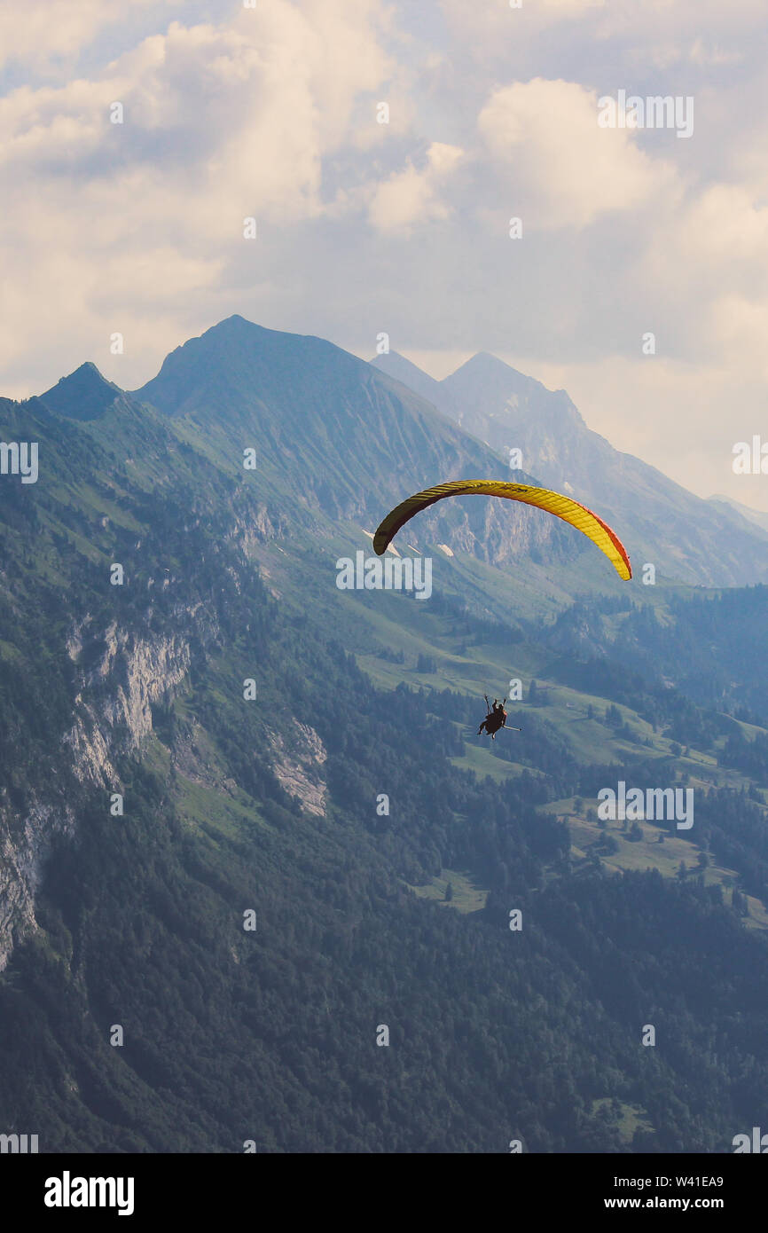 La fotografía vertical de tandem paragliding en Interlaken, Suiza en caso de mal tiempo. Volando sobre los Alpes Suizos en verano. Deportes de aventura extrema. Parapentes. Concepto, conceptual. Foto de stock