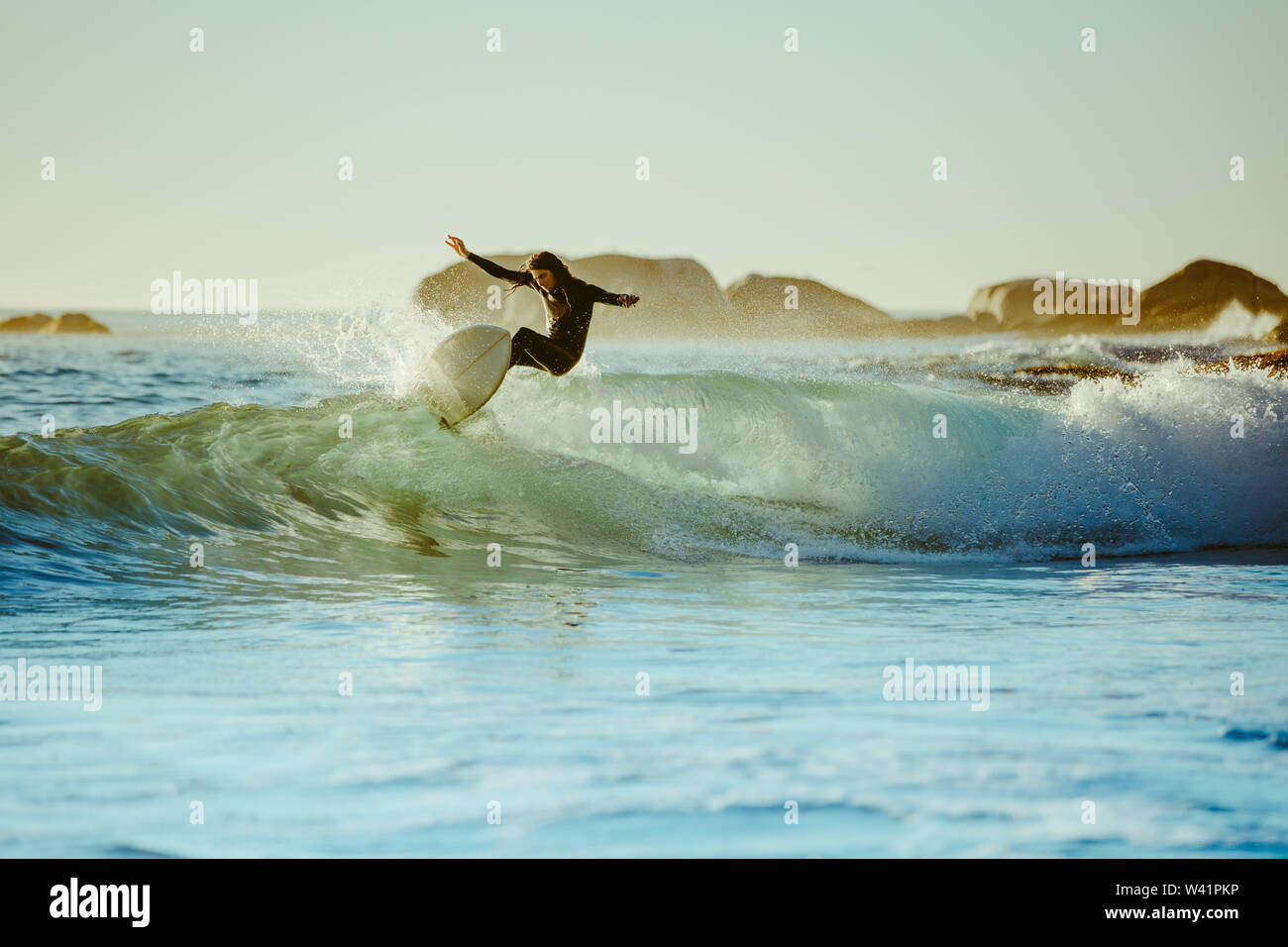 Joven navegando en las aguas del mar. Surfista masculino en el agua del océano con tabla de surf. Foto de stock
