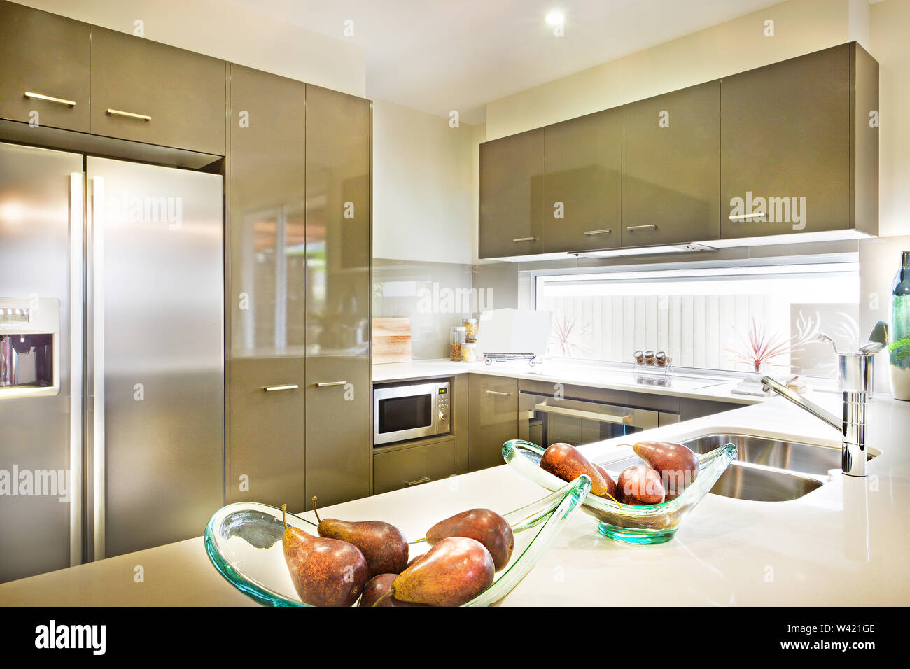 Las frutas en el tazón de vidrio en el mostrador de la cocina con nevera y  despensa y microondas junto a las ventanas de vidrio Fotografía de stock -  Alamy