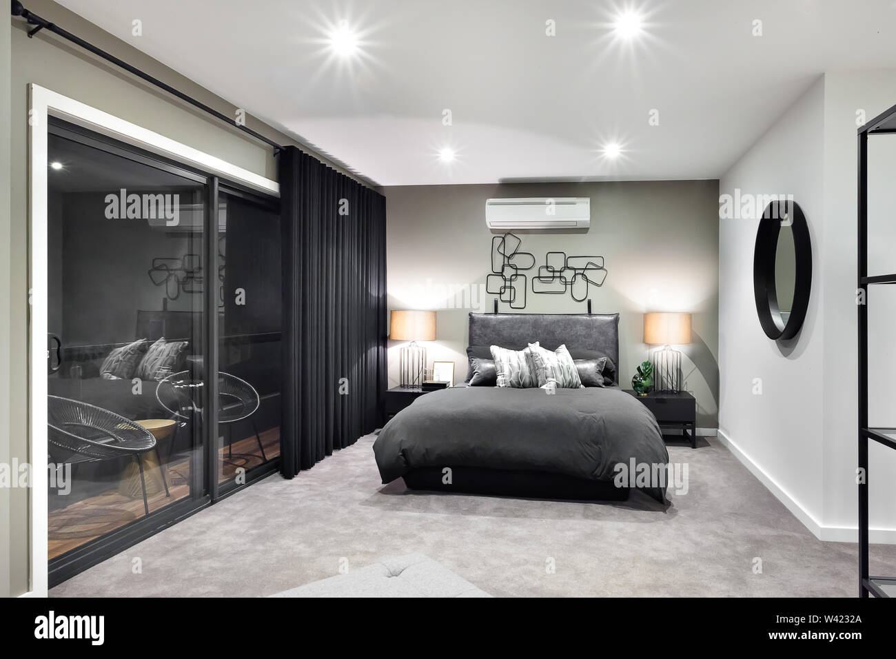 Cama de color negro en el lujoso hotel o casa con las luces intermitentes  al lado de una puerta o ventana de vidrio Fotografía de stock - Alamy