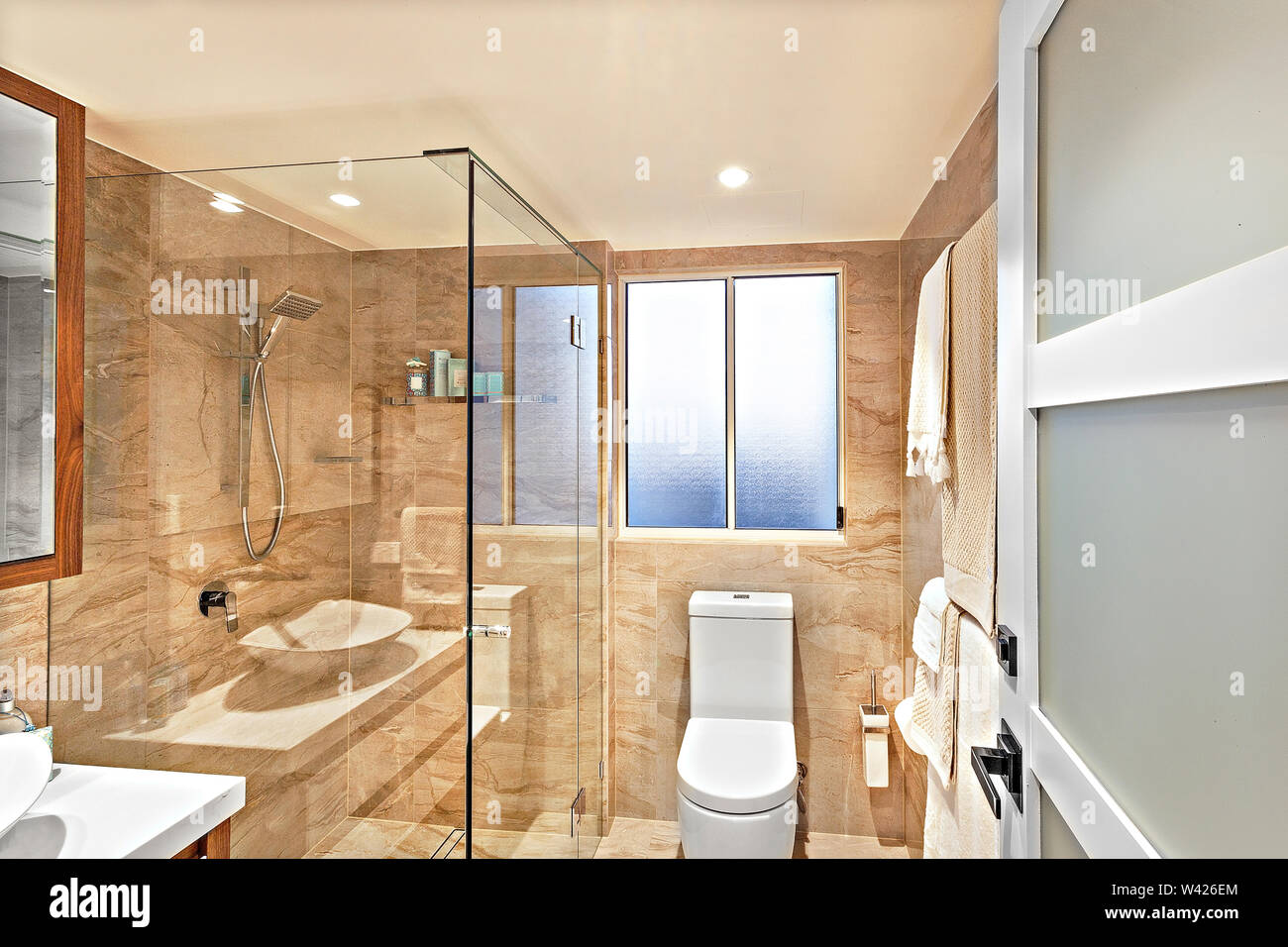 Un moderno cuarto de baño con una ducha separada con cristal, una zona de  aseo, toallas y perchas Fotografía de stock - Alamy