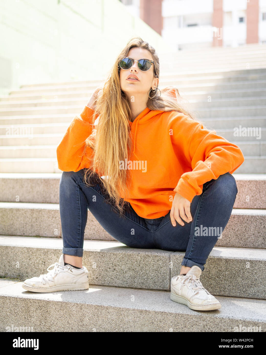 Retrato de ciudad positiva de mujeres jóvenes de color naranja. Fondo gris Fotografía de stock - Alamy