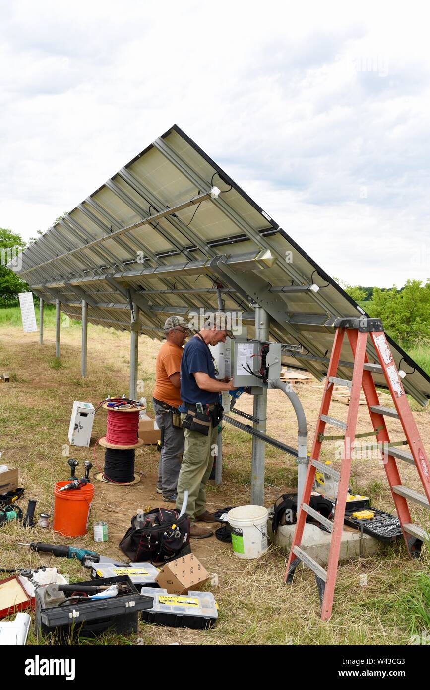 Electricistas instalación eléctrica solar (fotovoltaica) sistema en un campo para generar electricidad a partir del sol, Wisconsin, EE.UU. Foto de stock