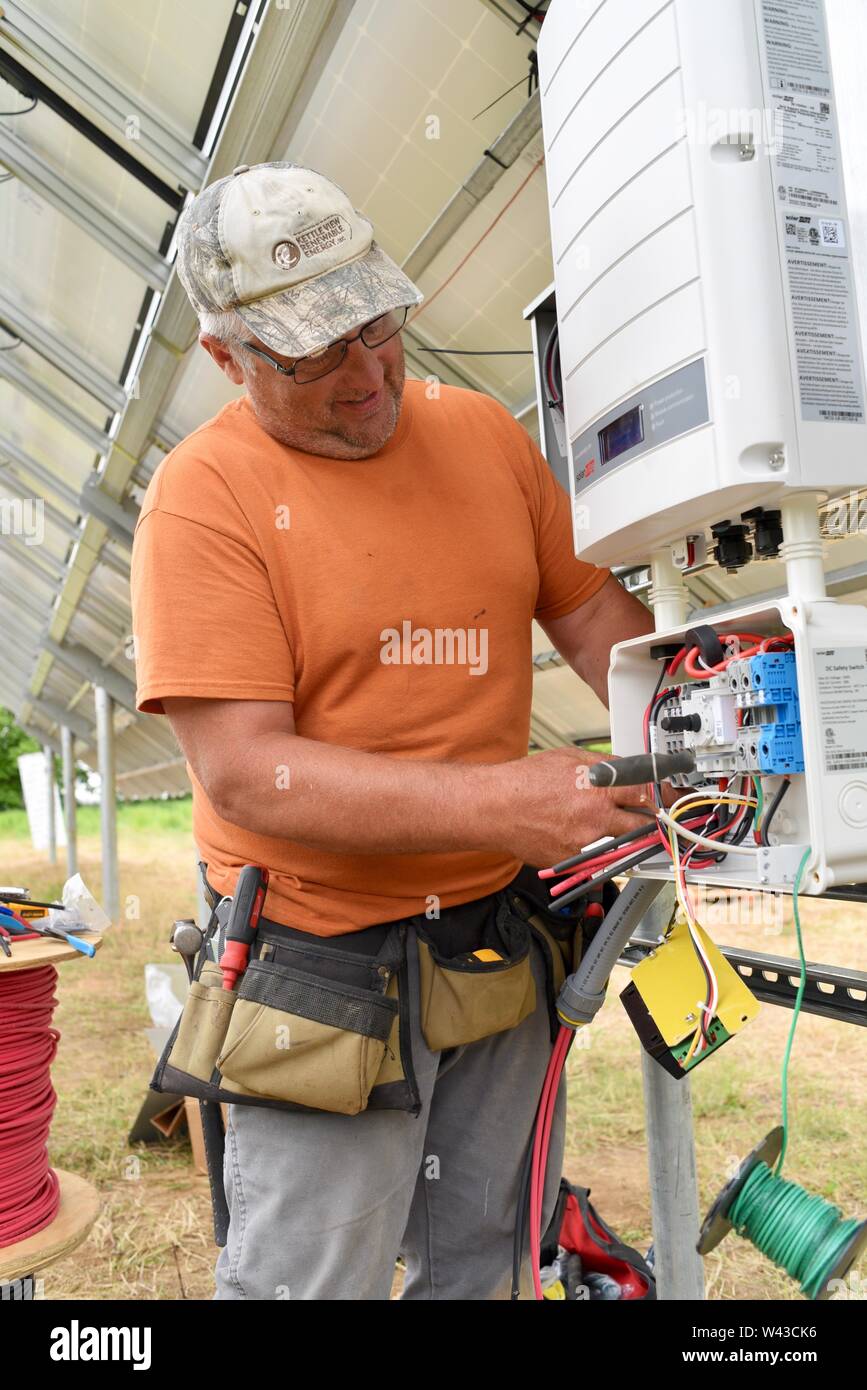 Electricistas instalación eléctrica solar (fotovoltaica) sistema en un campo para generar electricidad a partir del sol, Wisconsin, EE.UU. Foto de stock