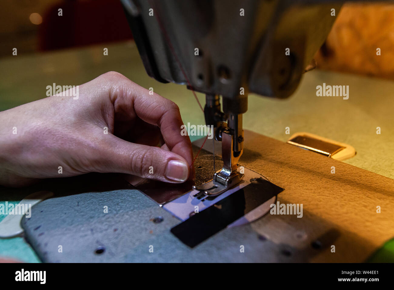 Un acercamiento en las manos de una joven costurera enhebrar una maquina de coser  industrial en taller, utilizando hilo rojo listo para crear nuevas prendas  Fotografía de stock - Alamy