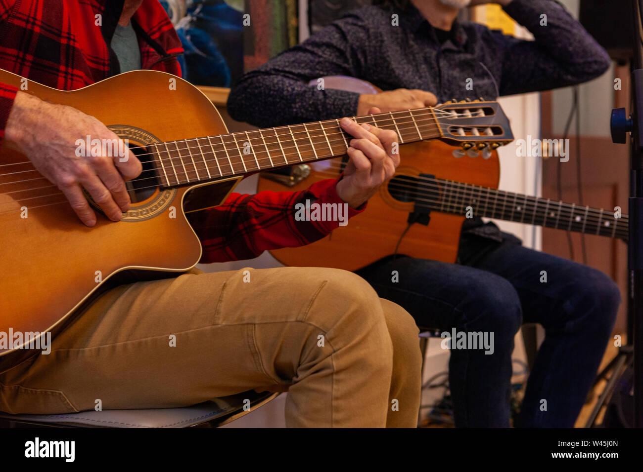 Una vista cercana de las manos de dos guitarristas, ya que realizar una obra musical sentarse adentro, hombres tocando instrumentos de cuerda con copia espacio en la derecha. Foto de stock