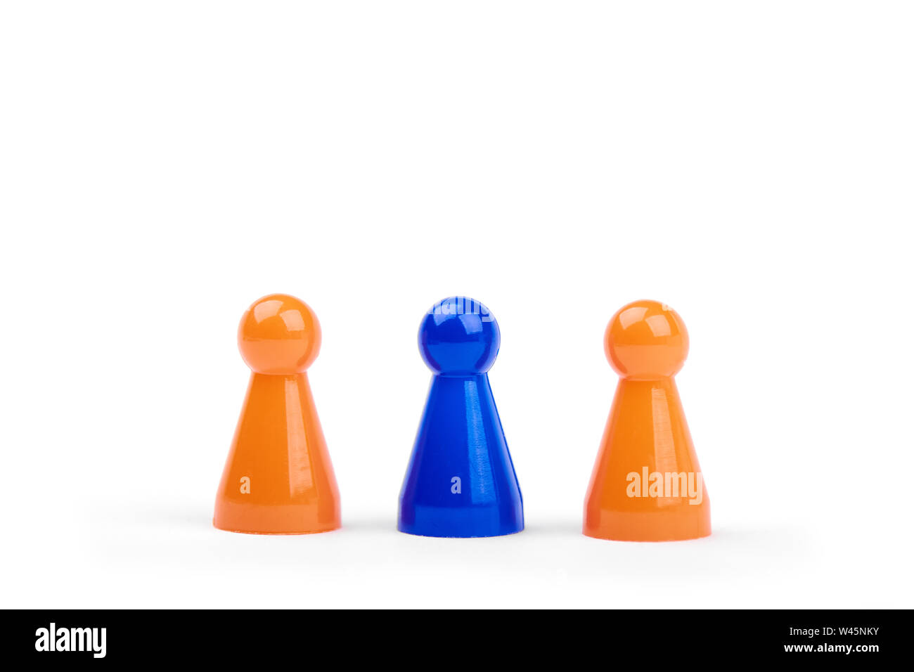 Jugar tres figuras de plástico. Dos naranja y uno diferente, aislado de figurillas azul sobre fondo blanco. Foto de stock
