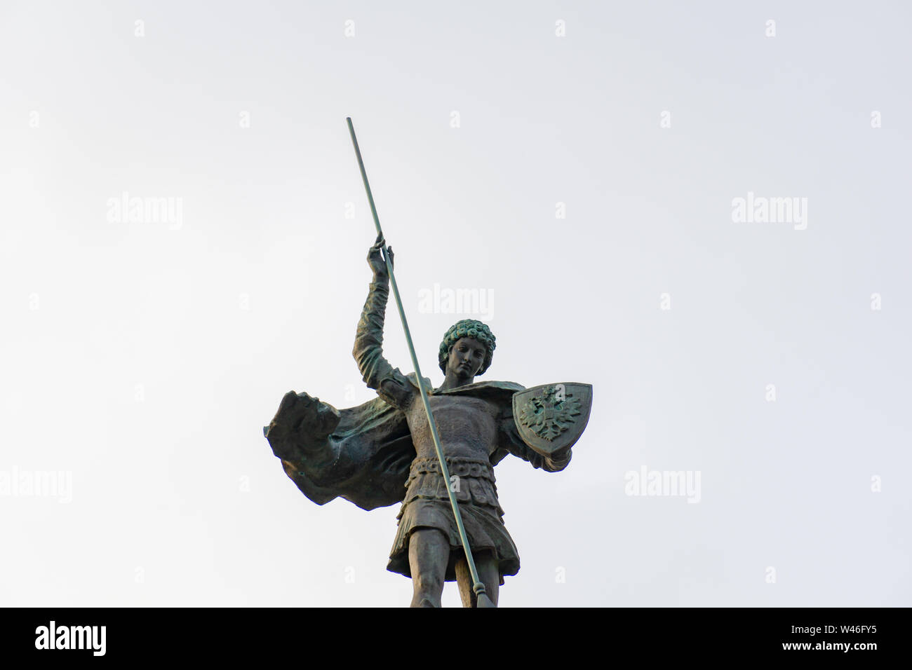 La estatua de un ángel apuntando hacia abajo con la punta de una lanza en la luna en el cielo gris Foto de stock
