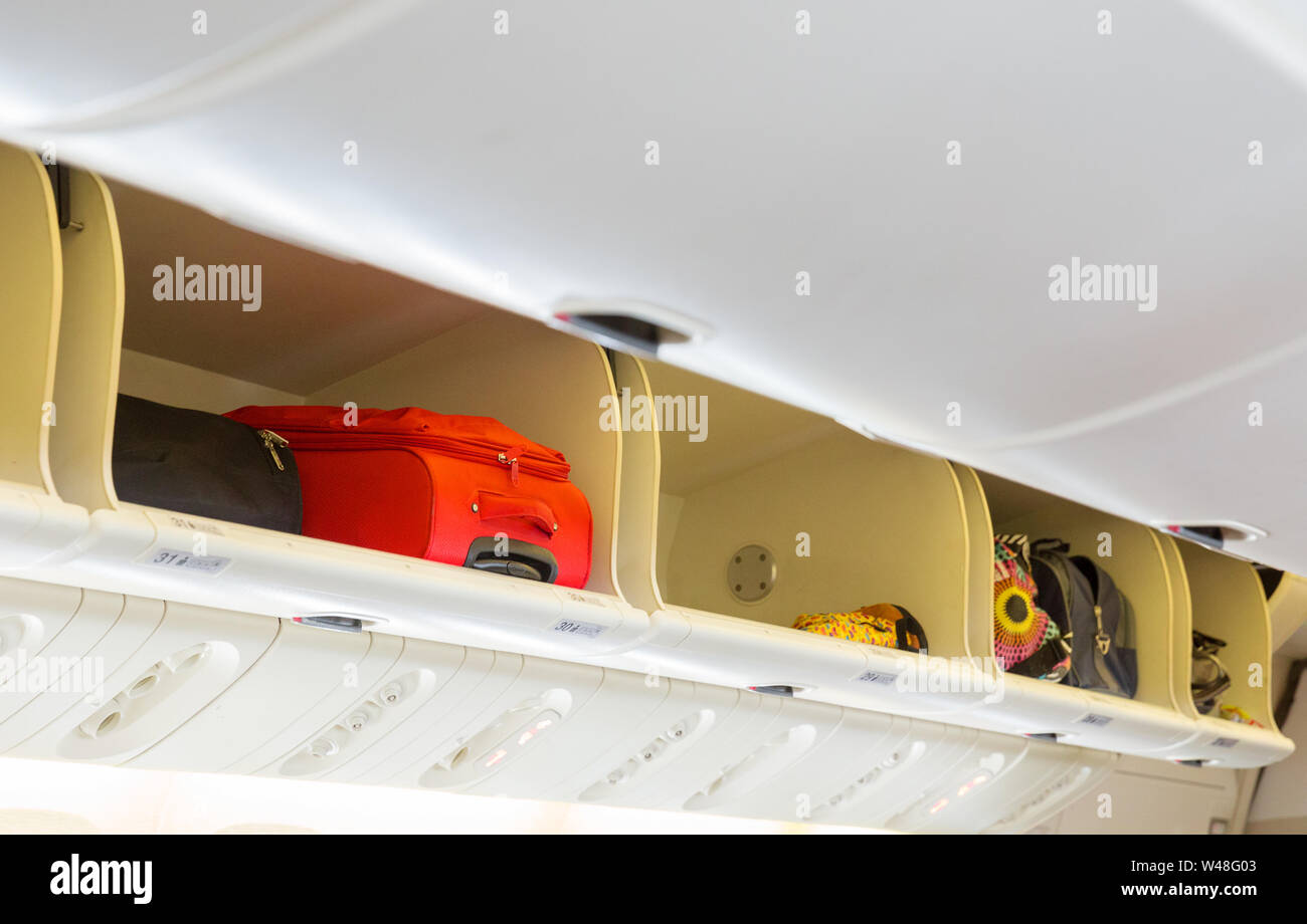 El equipaje de mano en el estante superior por encima de la cabeza en la cabina del avión Foto de stock