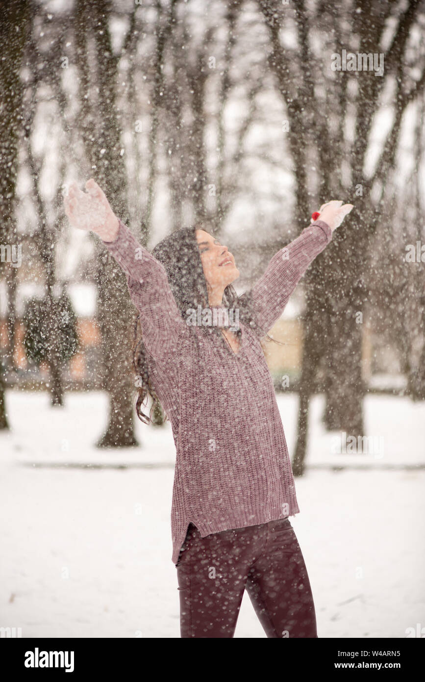 Hermosa joven mujer es disfrutar de la nieve la dispersión en el aire, emociones positivas, la alegría y la felicidad. Diversión de invierno al aire libre. Foto de stock